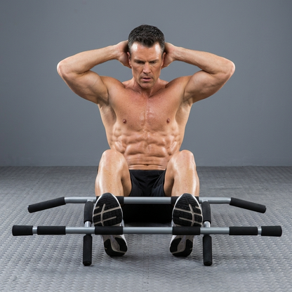 A shirtless man performing a sit-up on a silver and black abdominal exercise machine against a gray studio background.