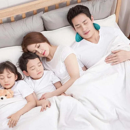 Family of four in a bed, with a child holding a teddy bear.